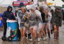 Festivalgoers shelter from the rain in plastic ponchos as they walk through the muddy site at the Reading Festival (Jeff Moore/PA)