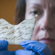 Curator Anna Forest examines fragment of 18th century hand written document discovered under the floorboards of Oxburgh Hall; Norfolk by archaeologists during a reroofing project. Picture: National Trust/Mike Hodgson