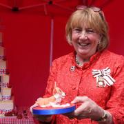 The Lady Dannatt MBE cuts the special six tier cake in Holt for the Queen's Platinum Jubilee earlier this year